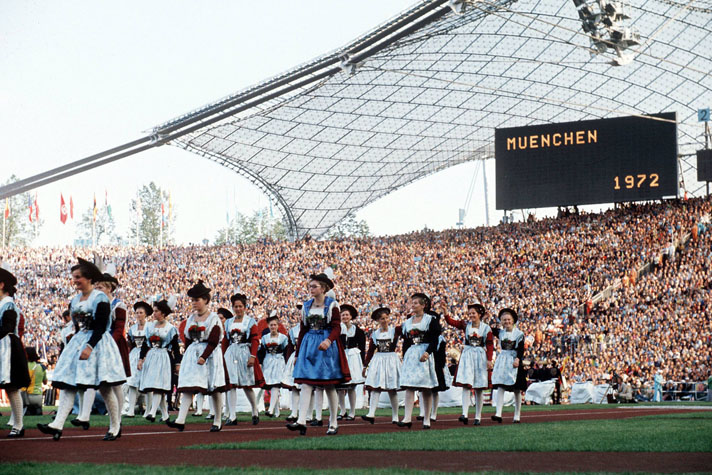 Fotografie einer Trachtengruppe in einem Stadion mit Publikum