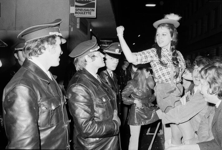 Schwarz-Weiß-Fotografie einer Frau, die einer Gruppe Polizisten droht