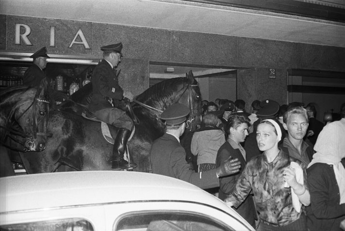 Schwarz-Weiß-Fotografie eine Menschenmenge, der sich berittene Polizei entgegen stellt.