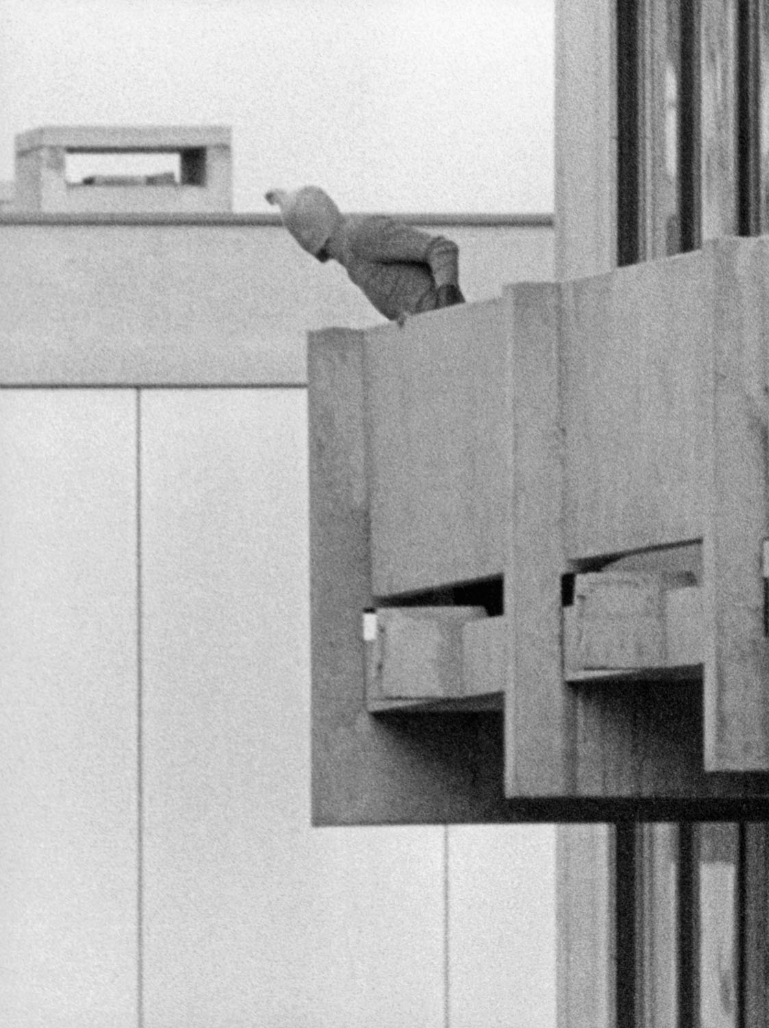 Schwarz-Weiß-Fotografie eines maskierten Mannes auf einem Balkon.