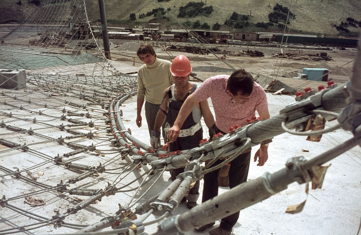 Fotografie von Bauarbeitern die ein Dachkonstrukt untersuchen
