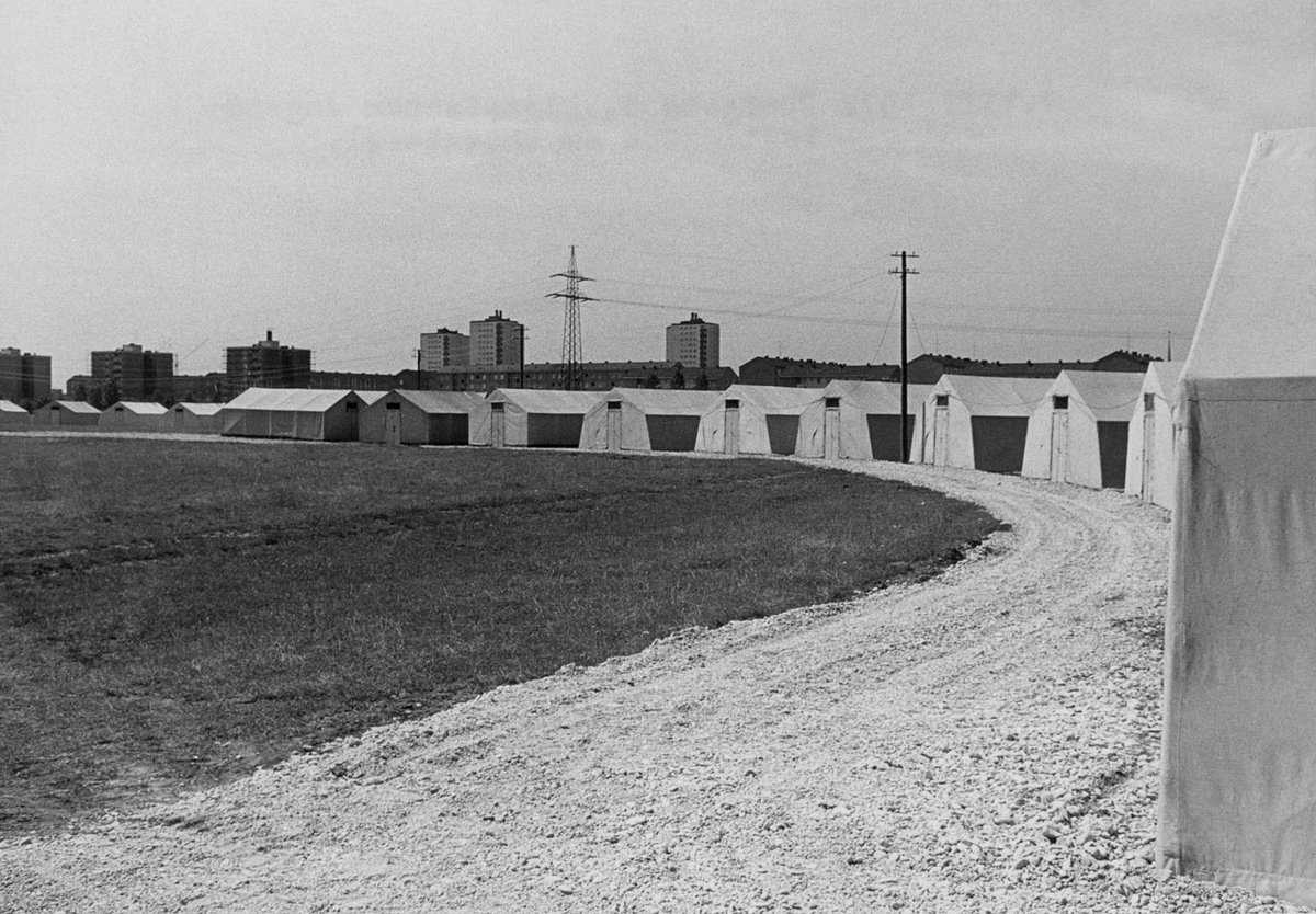 Schwarz-Weiß-Fotografie von einem Kiesweg mit verschiedenen Zelten