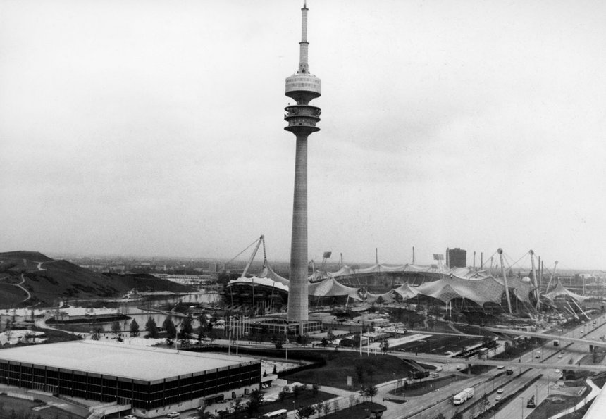 Schwarz-Weiß-Fotografie eines Fernsehturms, einer Halle und eines großes Stadions