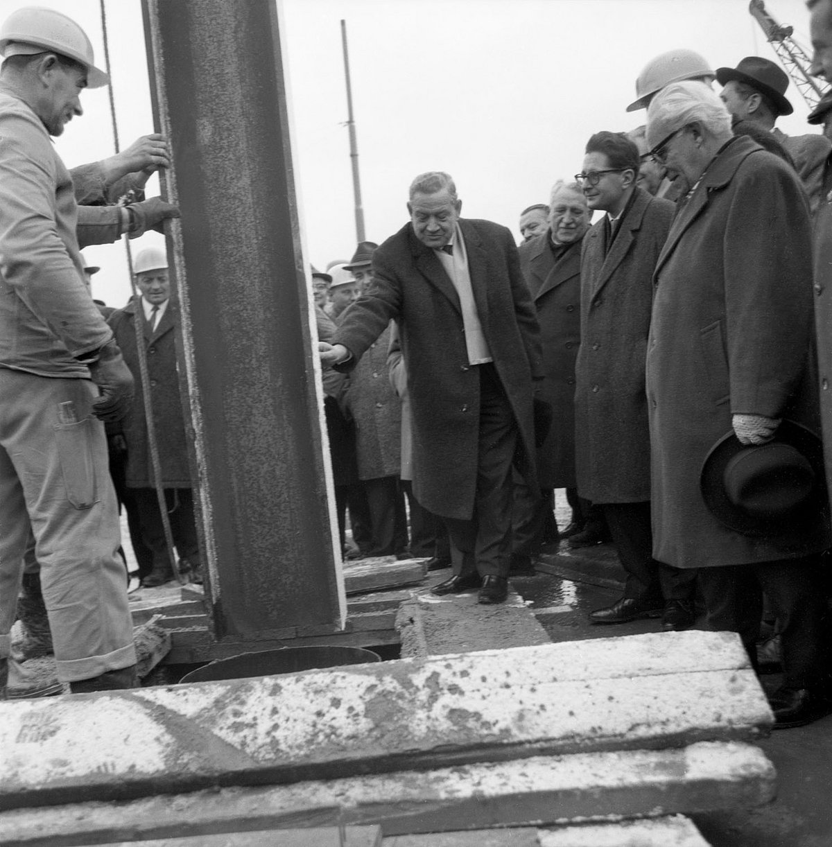 Schwarz-Weiß-Fotografie einer Baustelle und einer Gruppe von Männern.