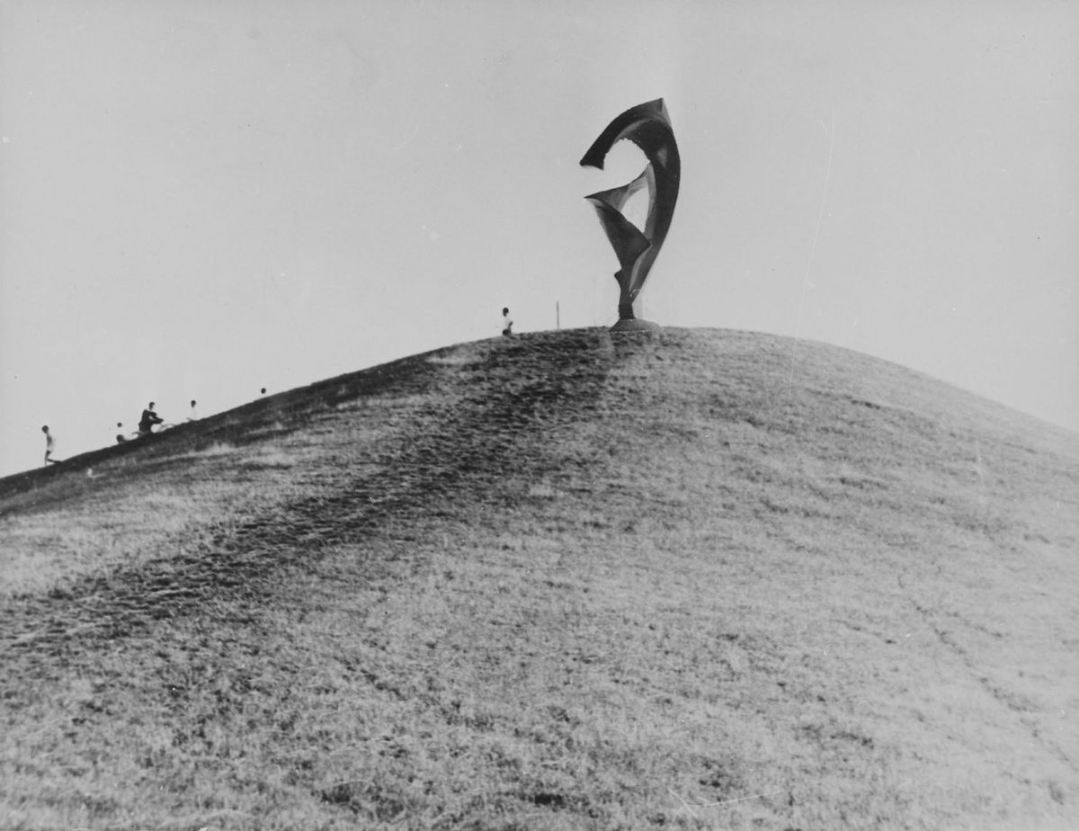 Schwarz-Weiß-Fotografie einer Skulptur die auf einem Berg steht