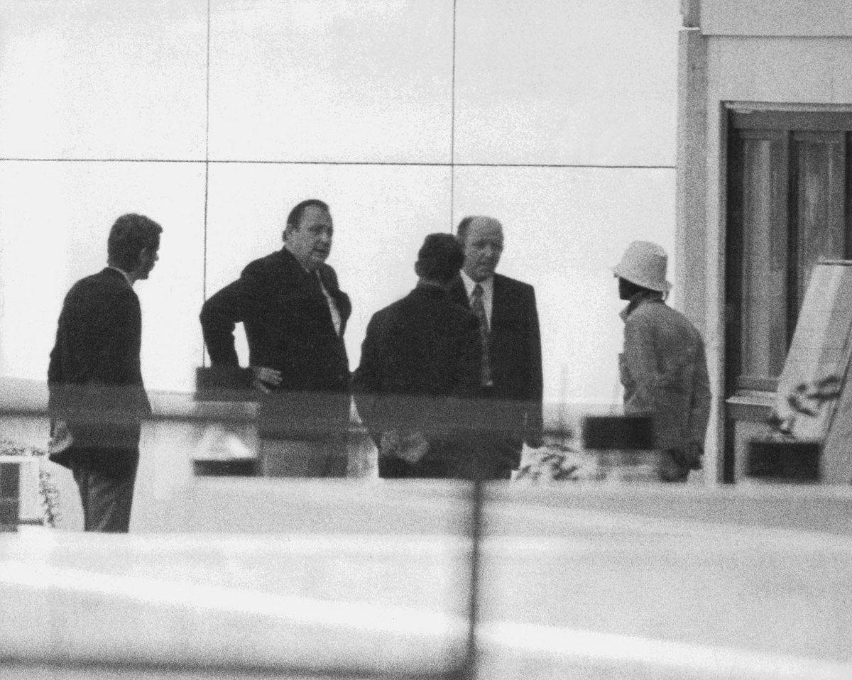 Schwarz-Weiß-Fotografie von fünf Männern die ein Gespräch führen.