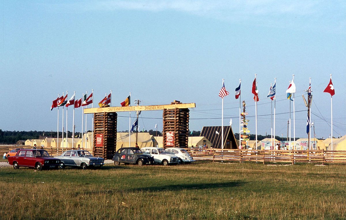 Fotografie eines Parkplatzes. Im Hintergrund befinden sich Flaggen und Zelte.