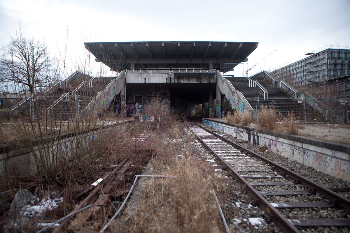 Fotografie von einem zweigleisigen Bahnhof, der von Gestrüpp überwuchert ist