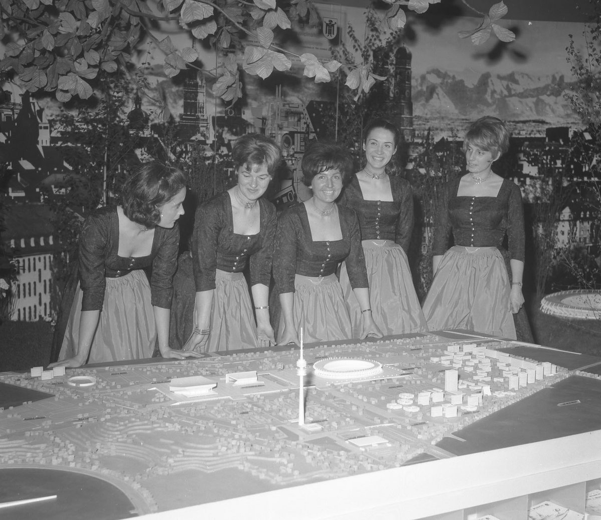Schwarz-Weiß-Fotografie einer Gruppe Frauen die vor einem Stadtmodell stehen
