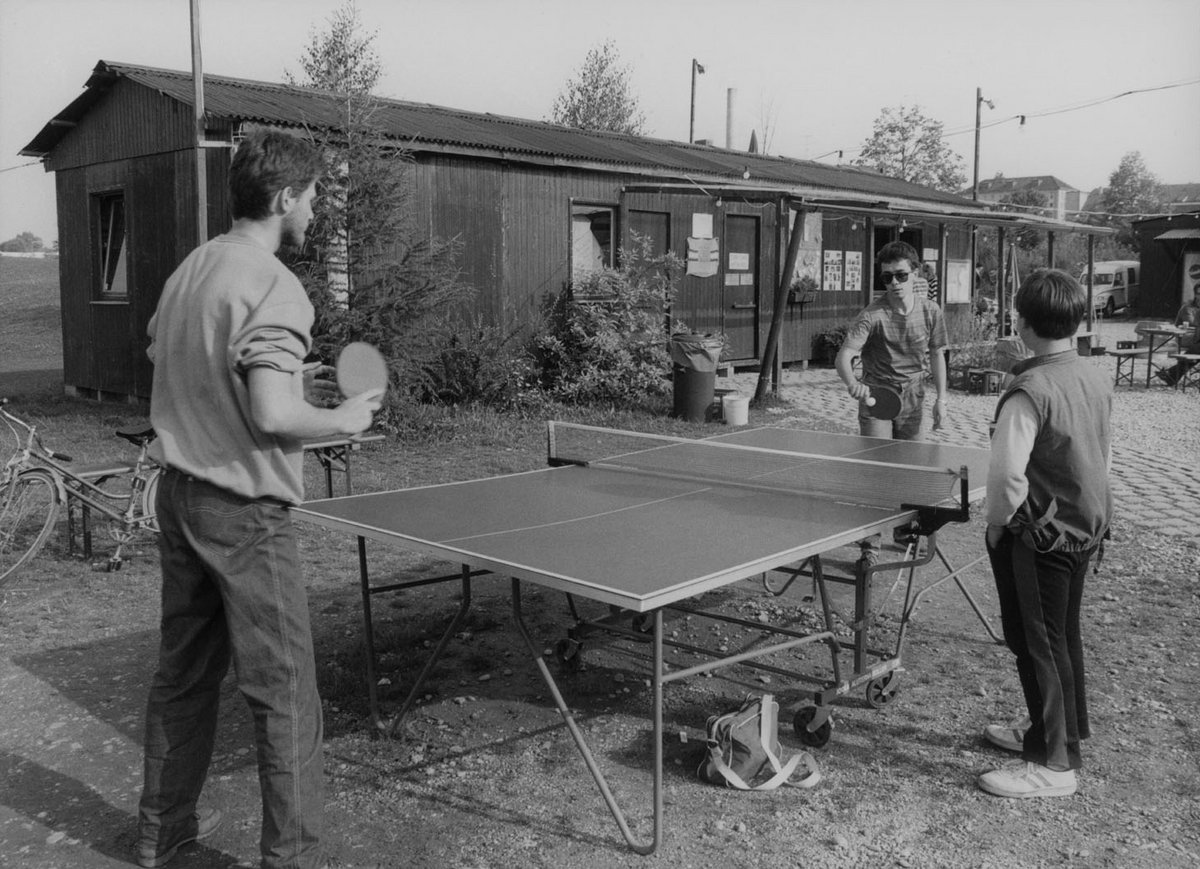 Schwarz-Weiß-Fotografie von drei Jugendliche die Tischtennis spielen.