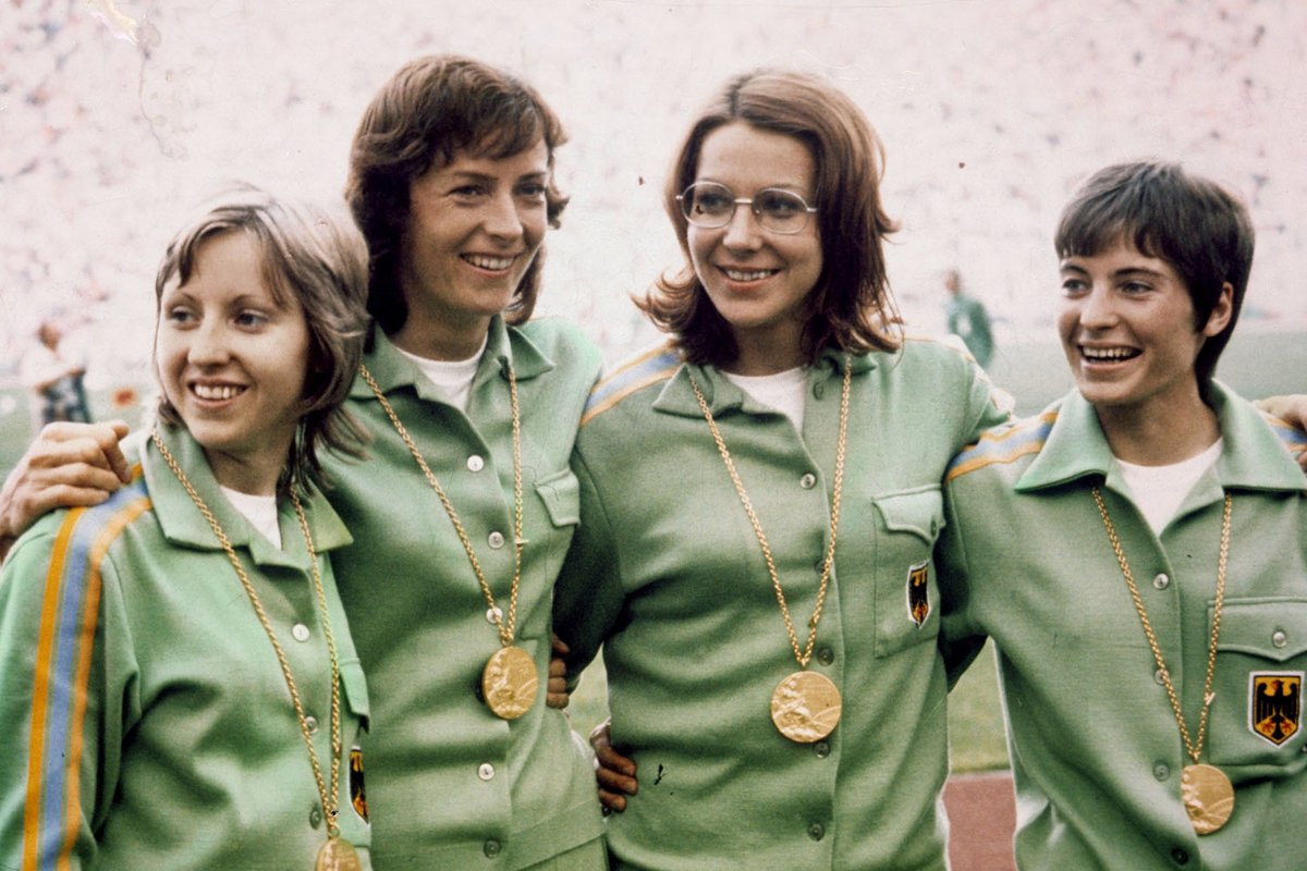 Fotografie von vier Frauen in Trainingsanzügen mit Goldmedaillen um den Hals.