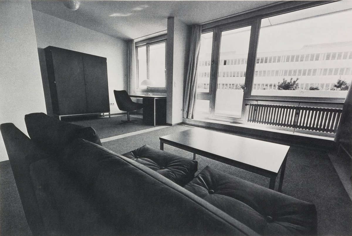 Schwarz-Weiß-Fotografie eines Wohnzimmers mit einer Couch und großen Fenstern