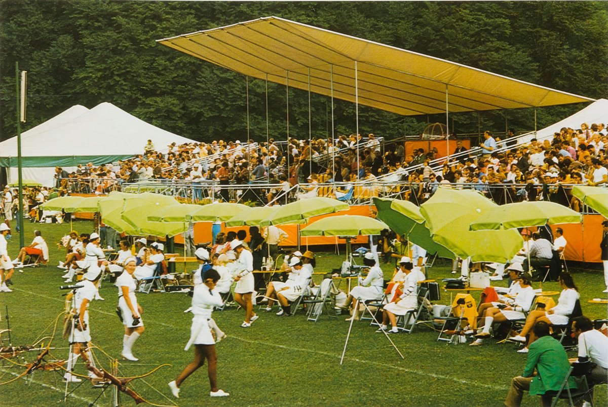 Fotografie einer Tribüne mit Publikum am Rand eines Sportplatzes
